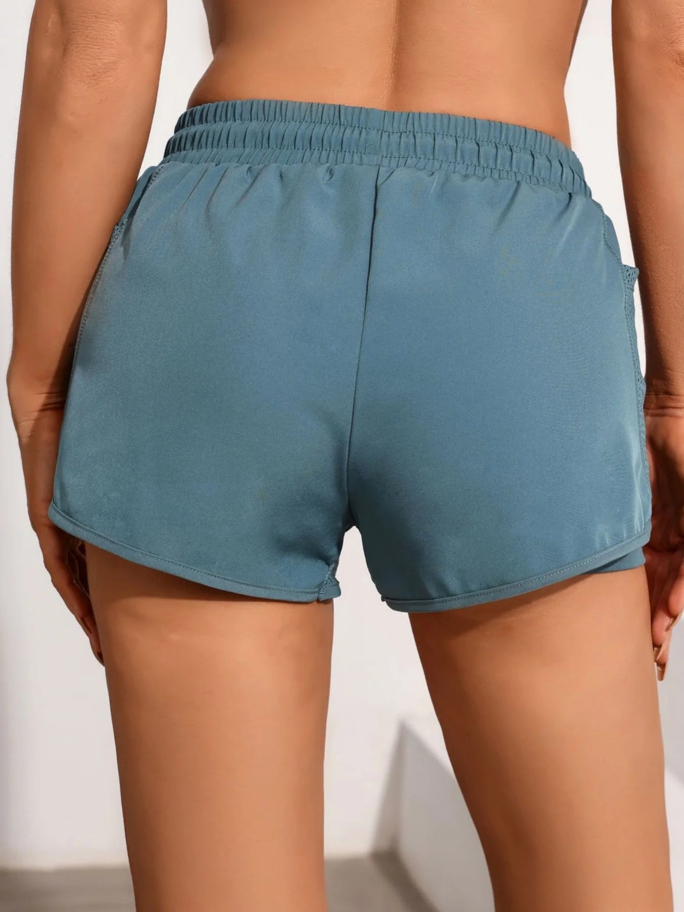 Back view of teal mesh workout shorts with high waistband and adjustable drawstring