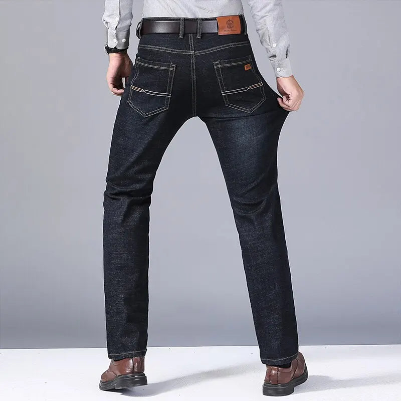 Back view showing stretch of slim-fit dark denim jeans worn by male model