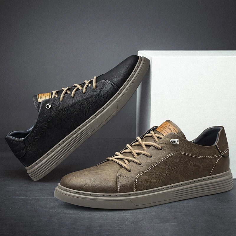 Black and taupe leather sneakers side by side on grey floor with white backdrop