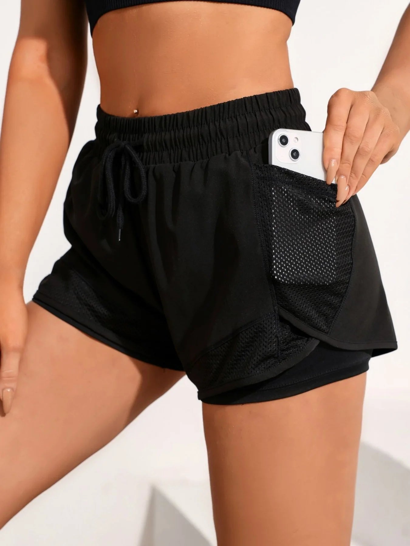 Black dual-layer workout shorts with phone in mesh pocket