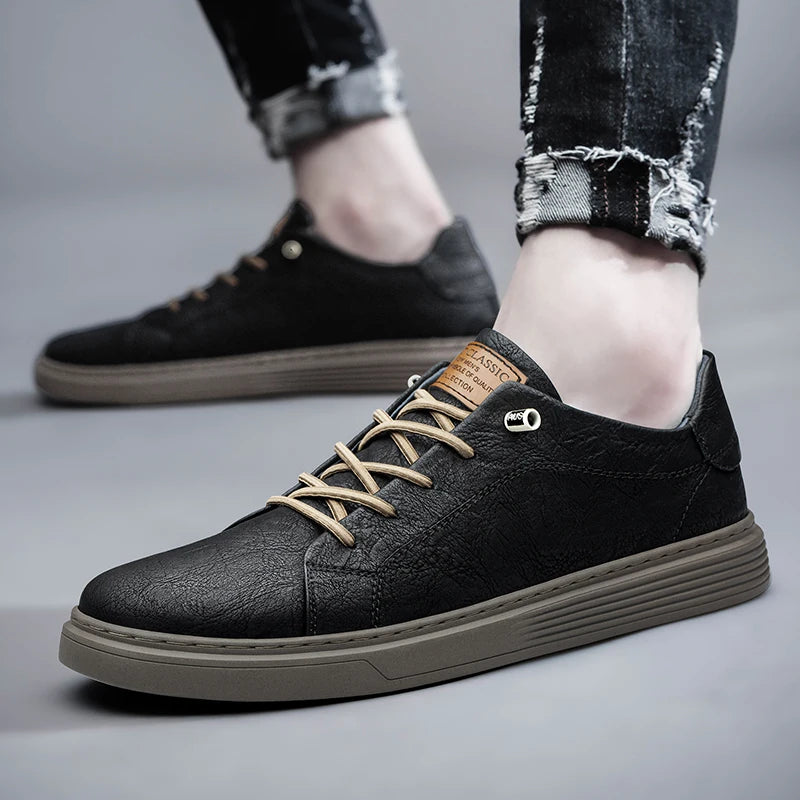 Black genuine leather sneakers worn with cuffed jeans, side view walking position