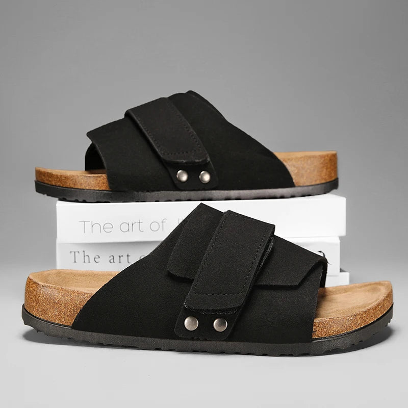 Black suede leather men's sandals with cork midsole displayed on stacked books