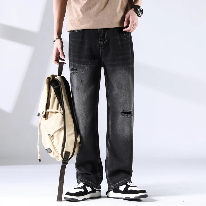 Black washed denim jeans with distressing and light gradient fade, front-facing model