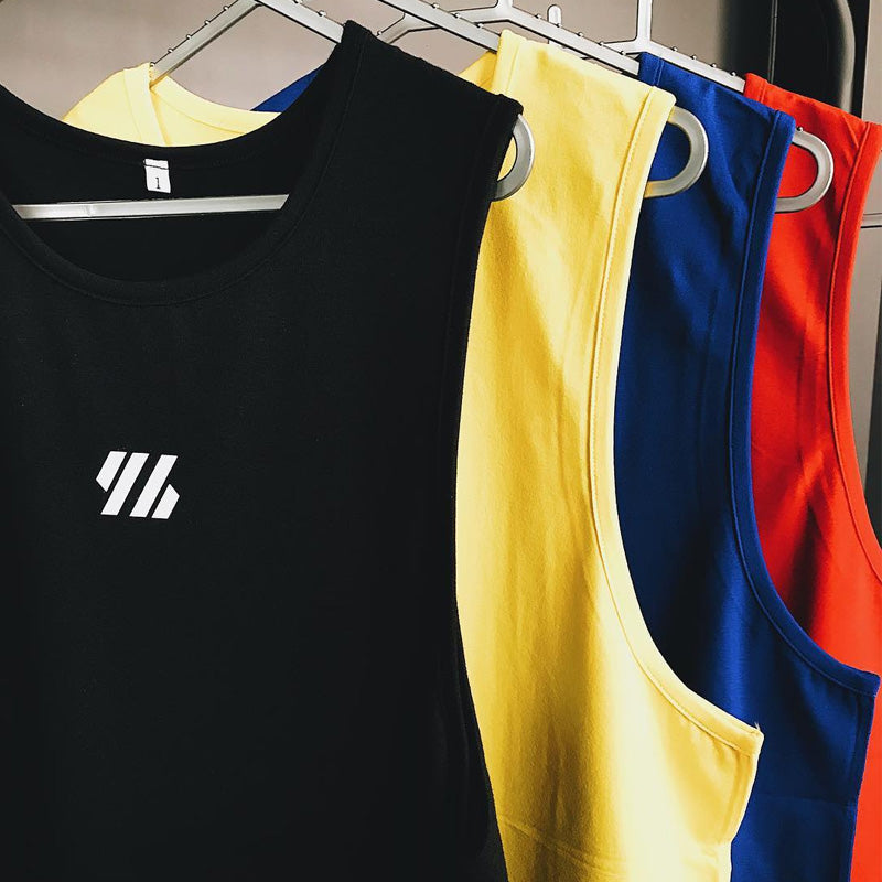 Black, yellow, blue, and red mesh gym tank tops hanging on clothing rack