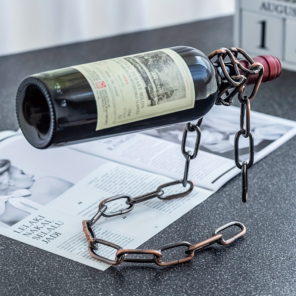Bronze chain wine holder with wine bottle angled over newspaper