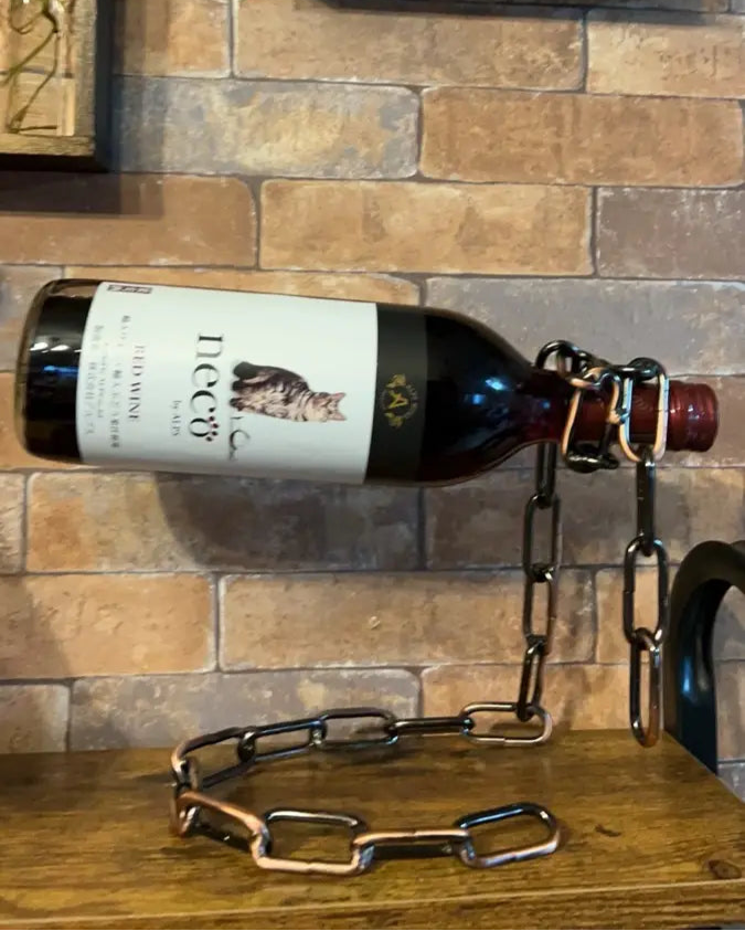Chrome chain holder suspending dark wine bottle in bar