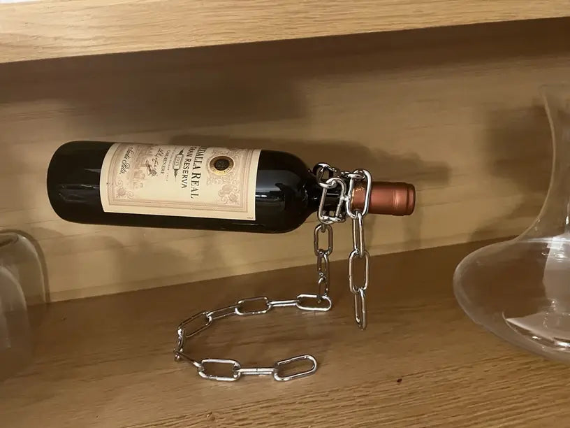 Chrome chain holder suspending dark wine bottle, side angle view