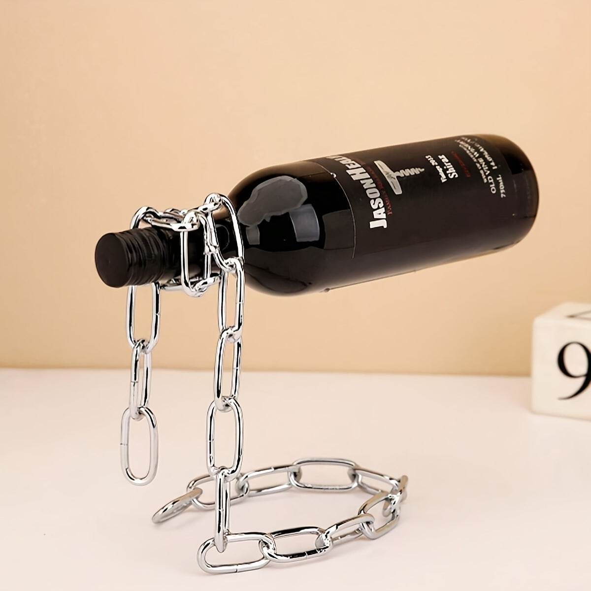 Chrome chain wine holder with wine bottle, minimal tan background