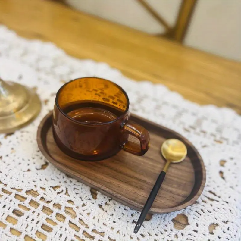 Clear glass cup with wooden spoon on Mokura solid wood tray held in both hands