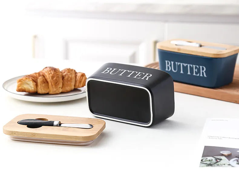 Close-up of croissant on plate with butter dish edge and stainless steel spreader nearby