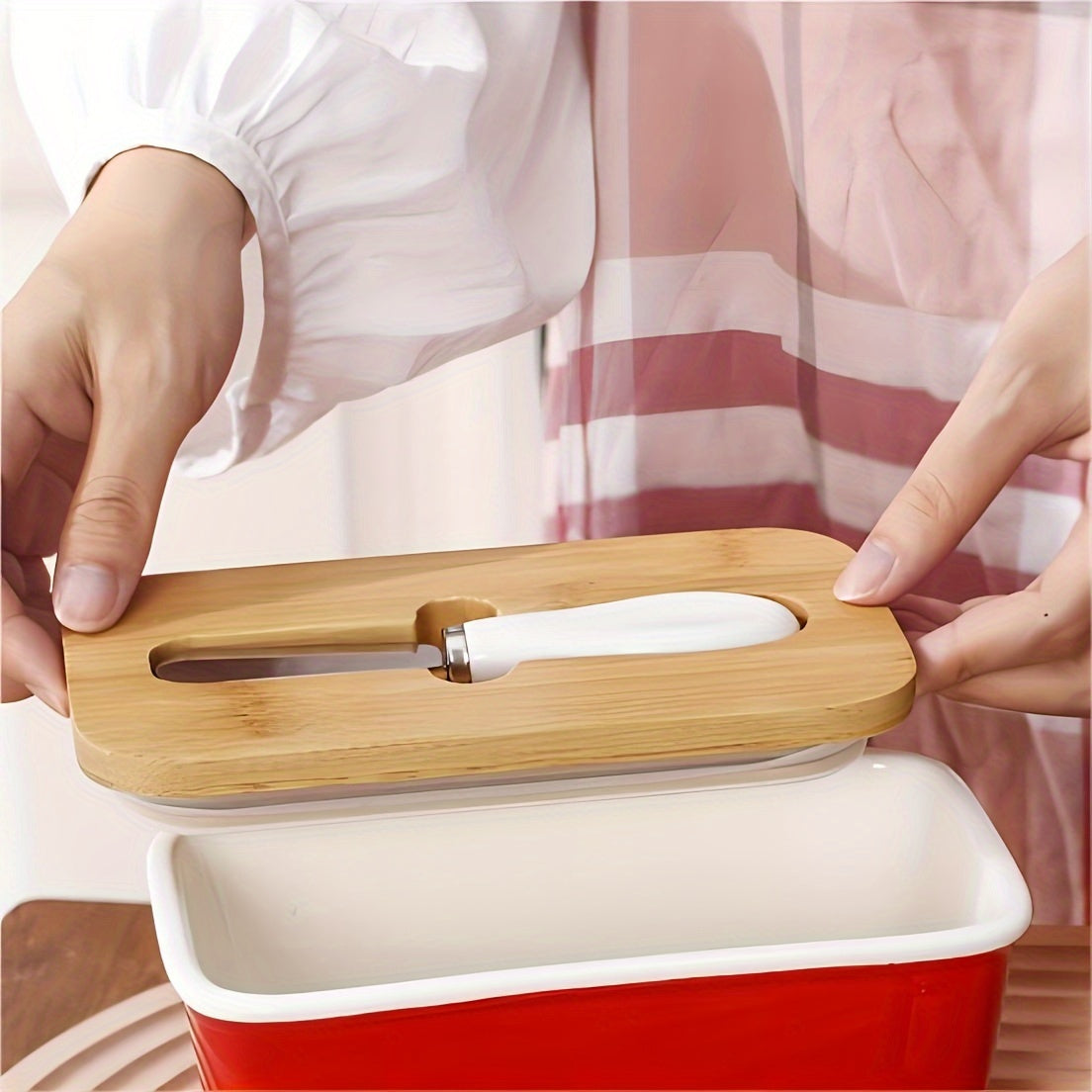 Close-up of croissant on plate with red butter dish edge and stainless steel spreader nearby