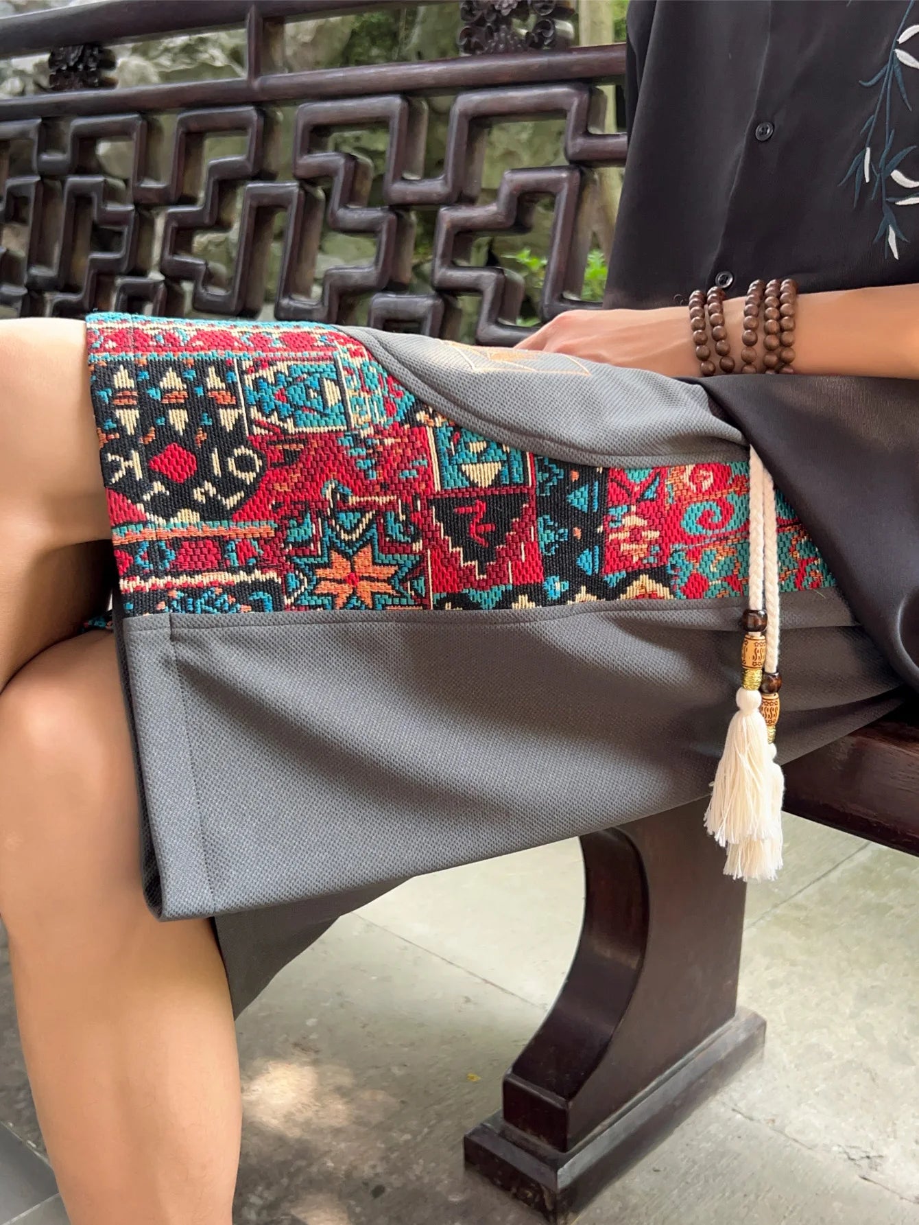Close-up of gray ethnic shorts showing woven patterns and tassel details