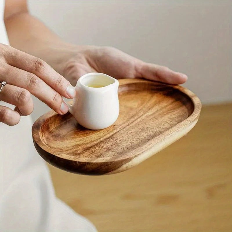 Close-up of hand placing white ceramic creamer on light acacia Mokura serving tray