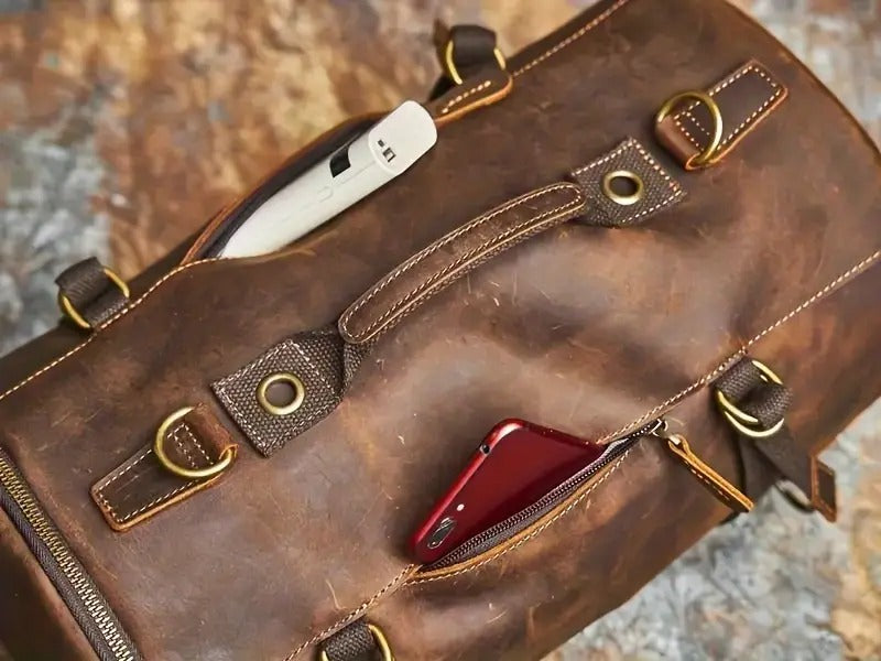Close-up of leather strap and zipper with visible red phone inside pocket