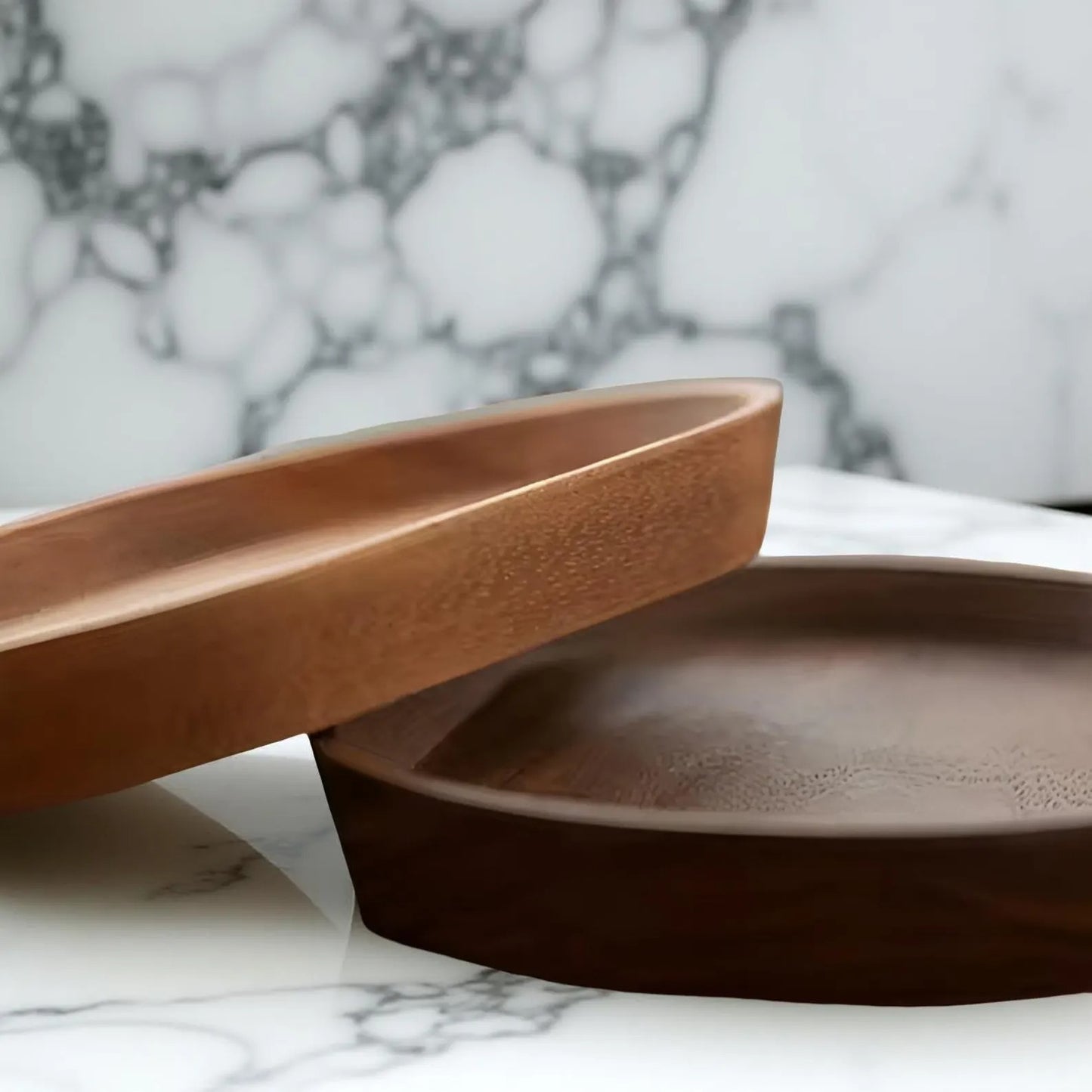 Close-up of two stacked Mokura wooden trays in cherry and walnut finish on marble counter