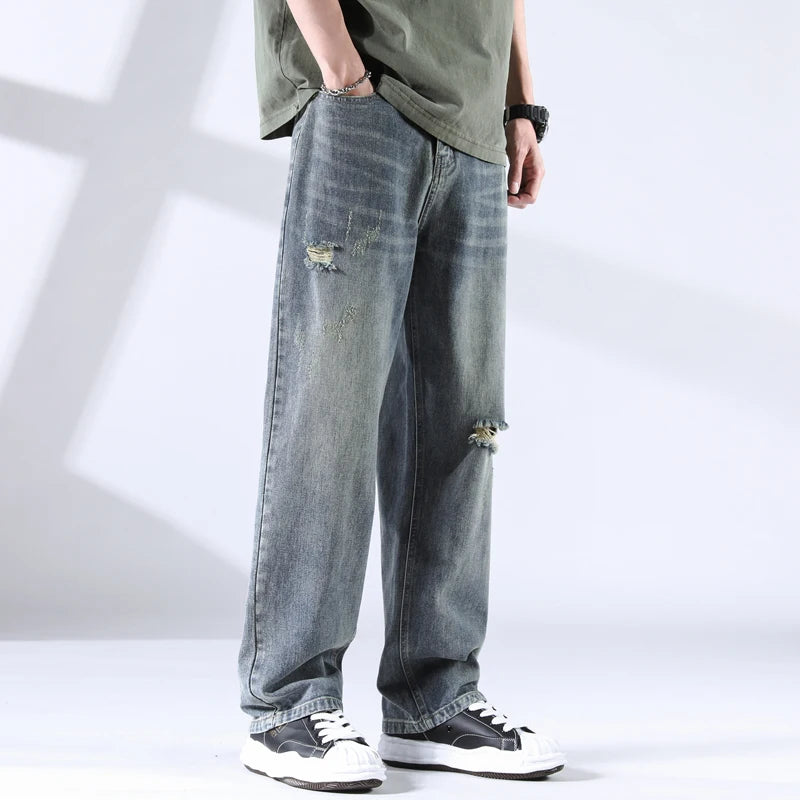 Close side-front view of storm grey-blue distressed jeans with soft fading and ripped knee