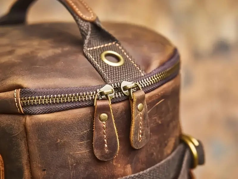Detail view of dual zipper closure and brass hardware on backpack top