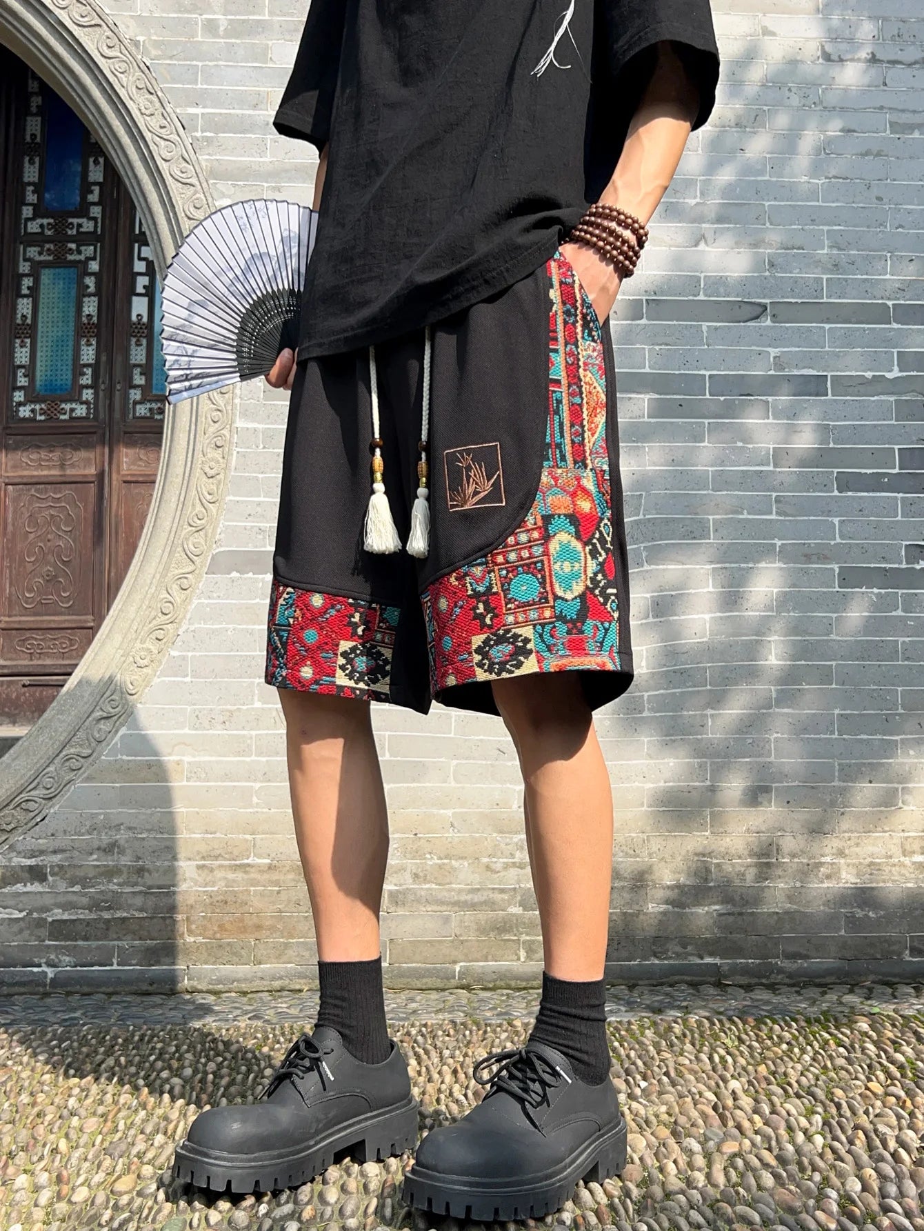 Front view of black ethnic shorts with bold woven trim and tassel drawstring