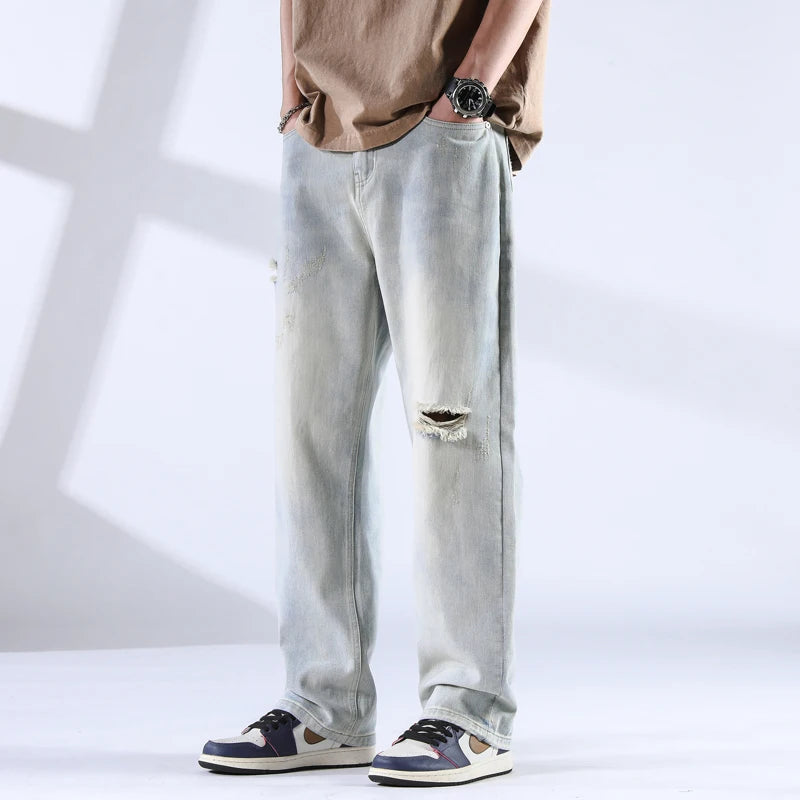 Front view of light ice-wash distressed jeans with knee rip and worn-in look, paired with sneakers
