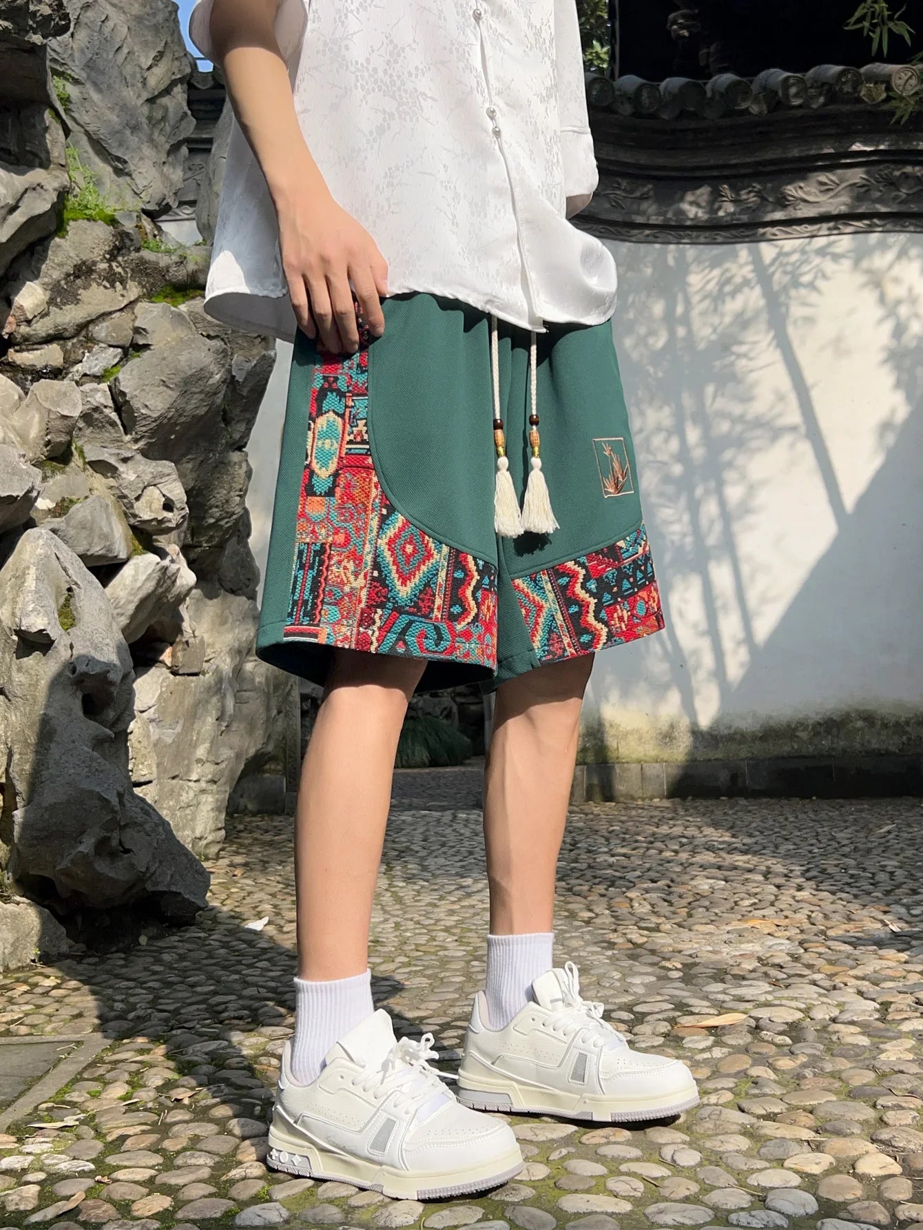 Full-body view of green patchwork shorts paired with white shirt and sneakers