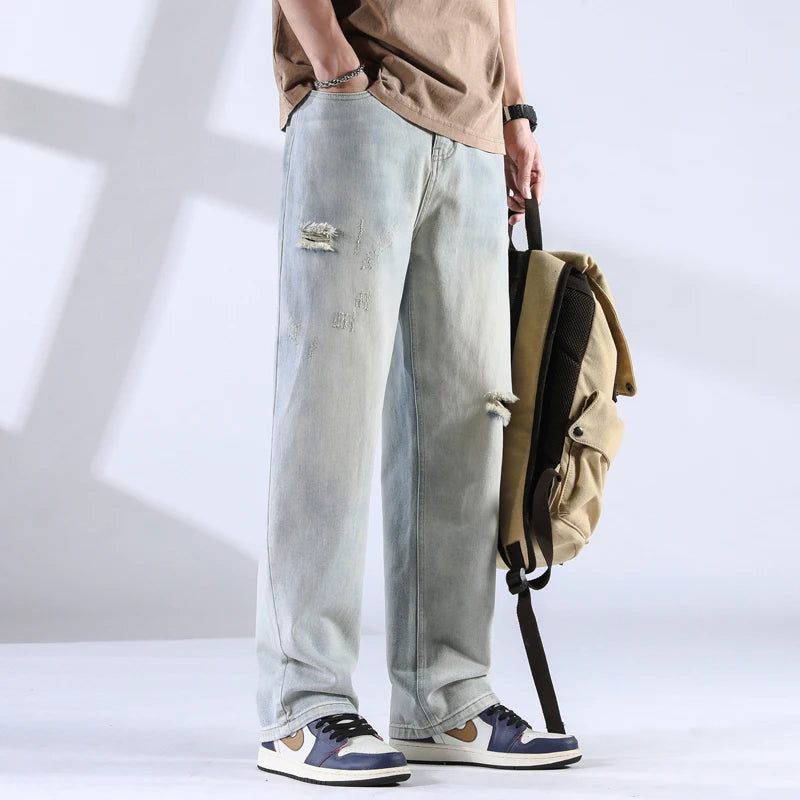 Full side view of relaxed fit jeans in faded grey-blue with frayed rip detail