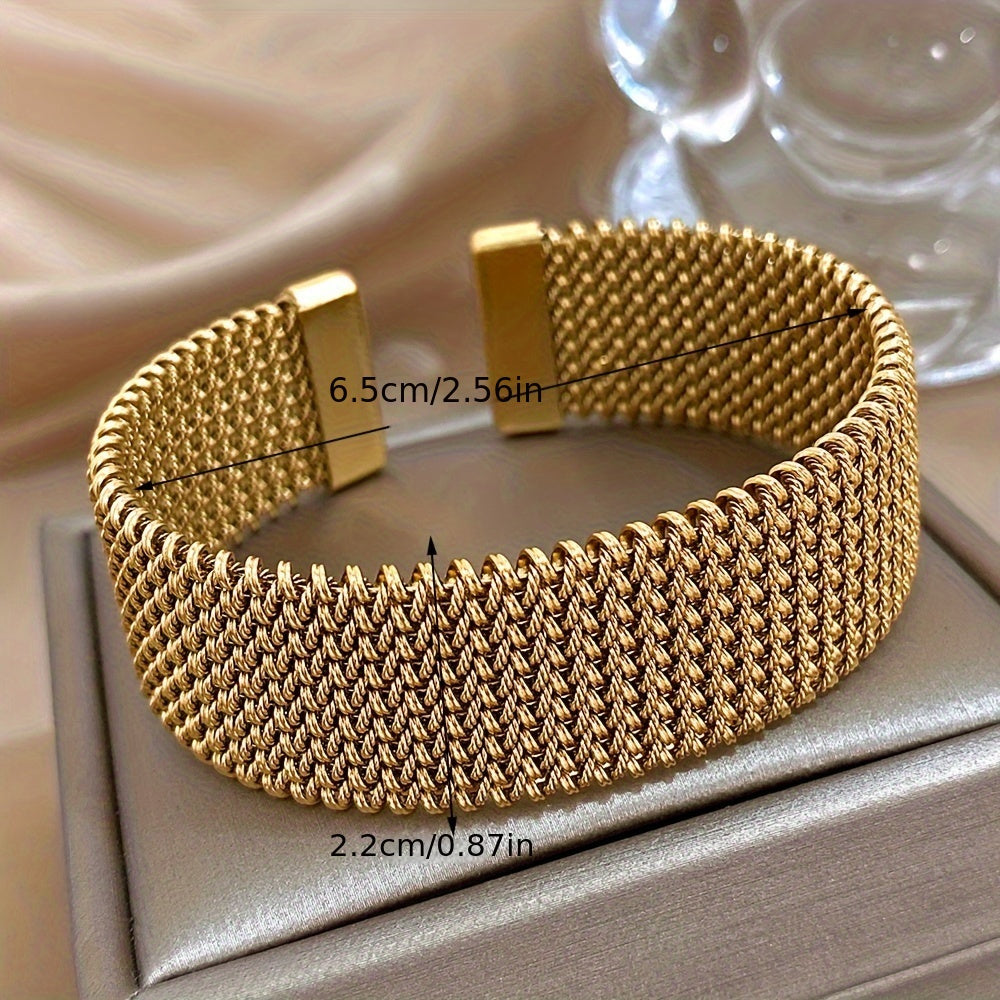 Gold bracelet with reflective mesh surface, resting on beige box top with dimension details