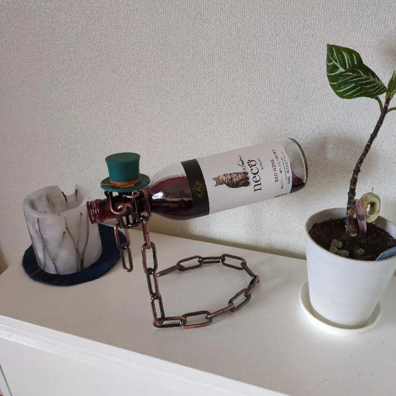 Gold chain wine holder with floral-decorated bottle and green plants
