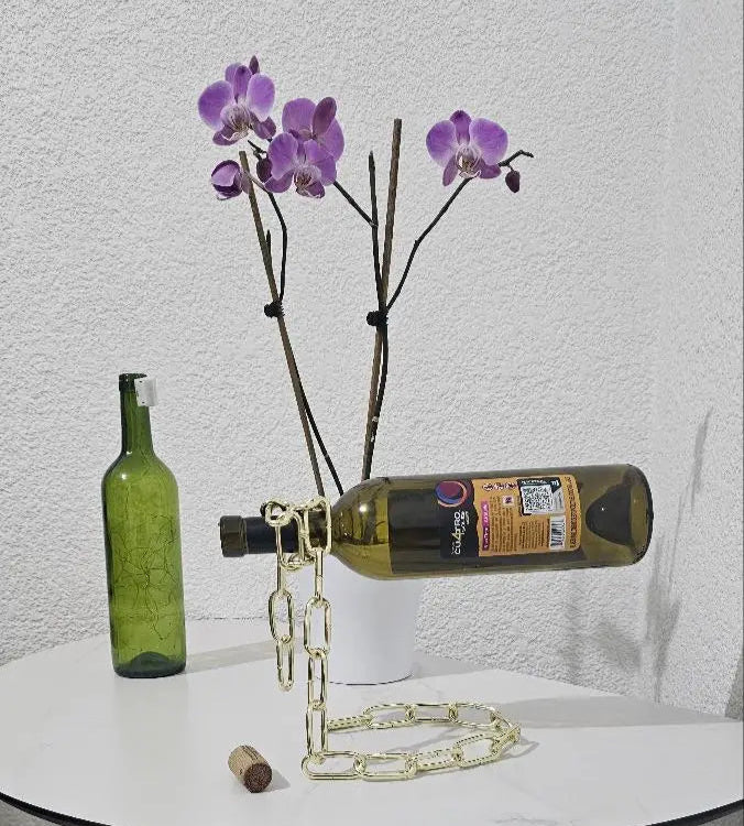 Gold chain wine holder with floral-decorated bottle and purple flowers