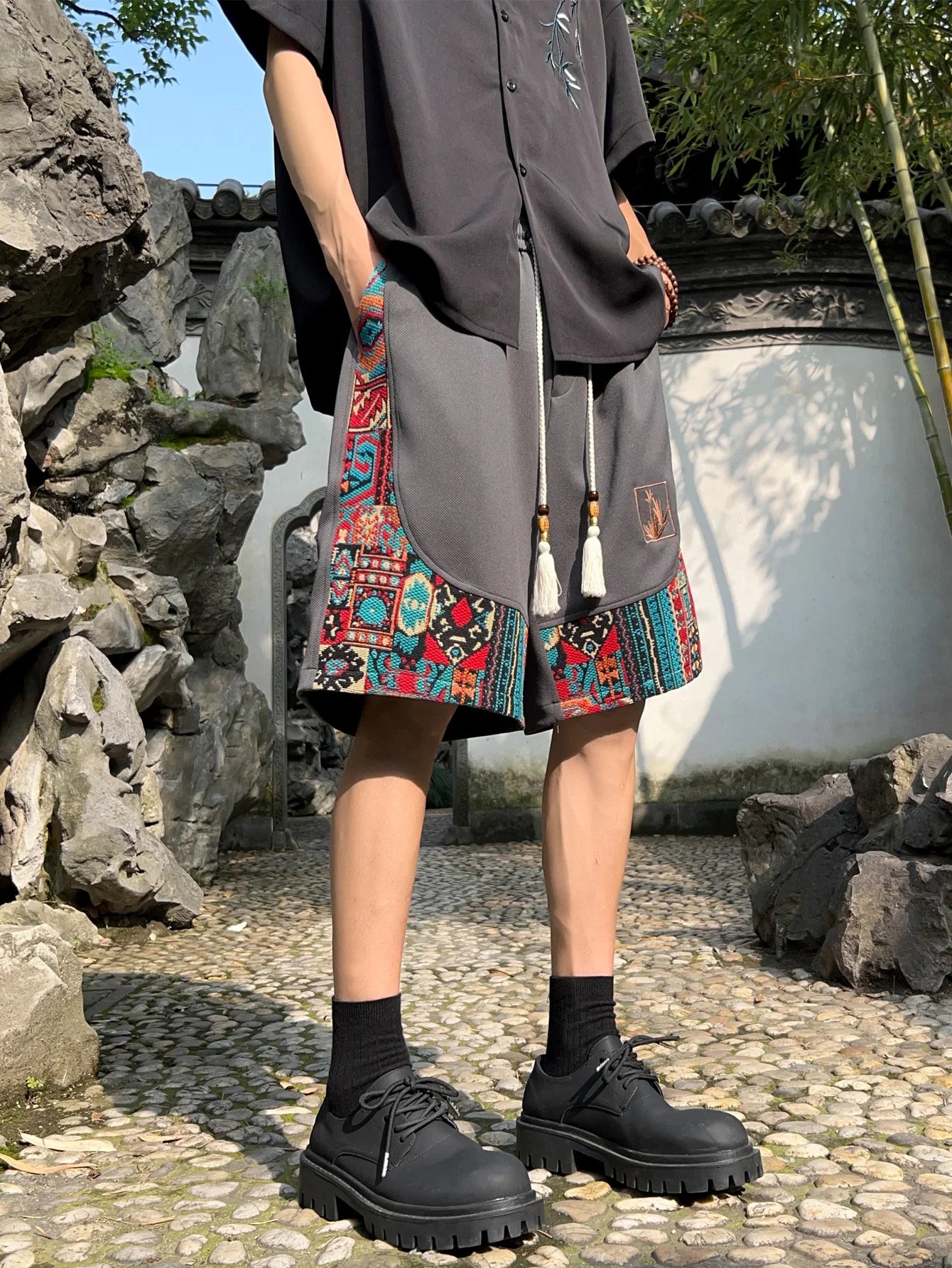 Gray ethnic shorts styled with black shirt, showing vibrant woven paneling