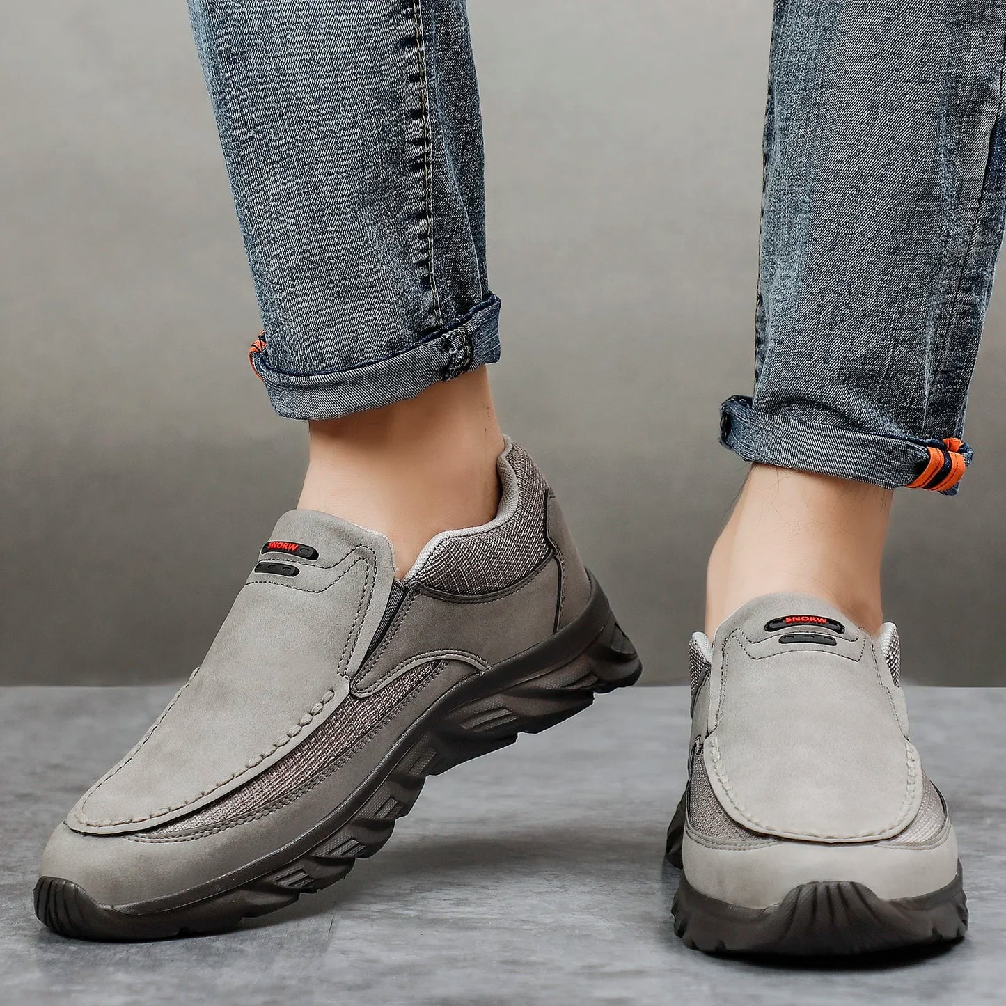 Grey leather casual loafers with mesh panels, worn with cuffed denim