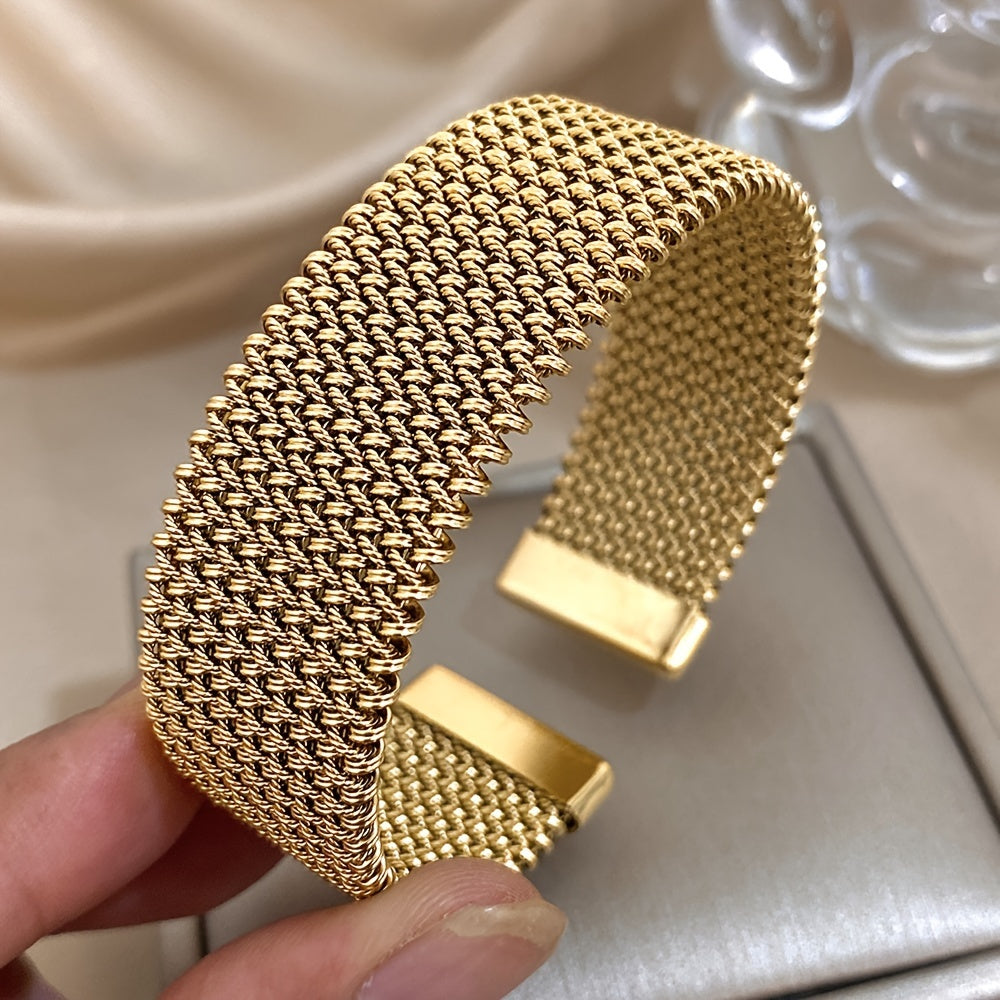 Hand holding gold-tone woven bracelet close-up
