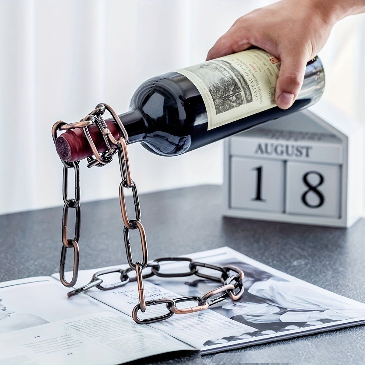 Hand placing bottle into bronze chain holder, August 18 calendar behind
