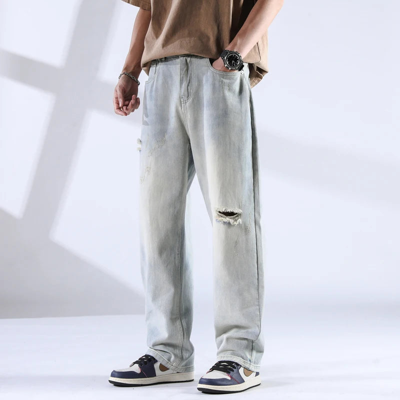 Light ice-wash distressed jeans with soft fading and tears, front view