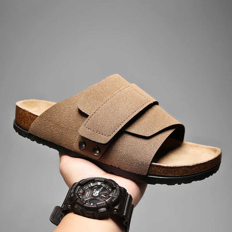 Light taupe suede slide sandal for men with cork footbed, held for side view