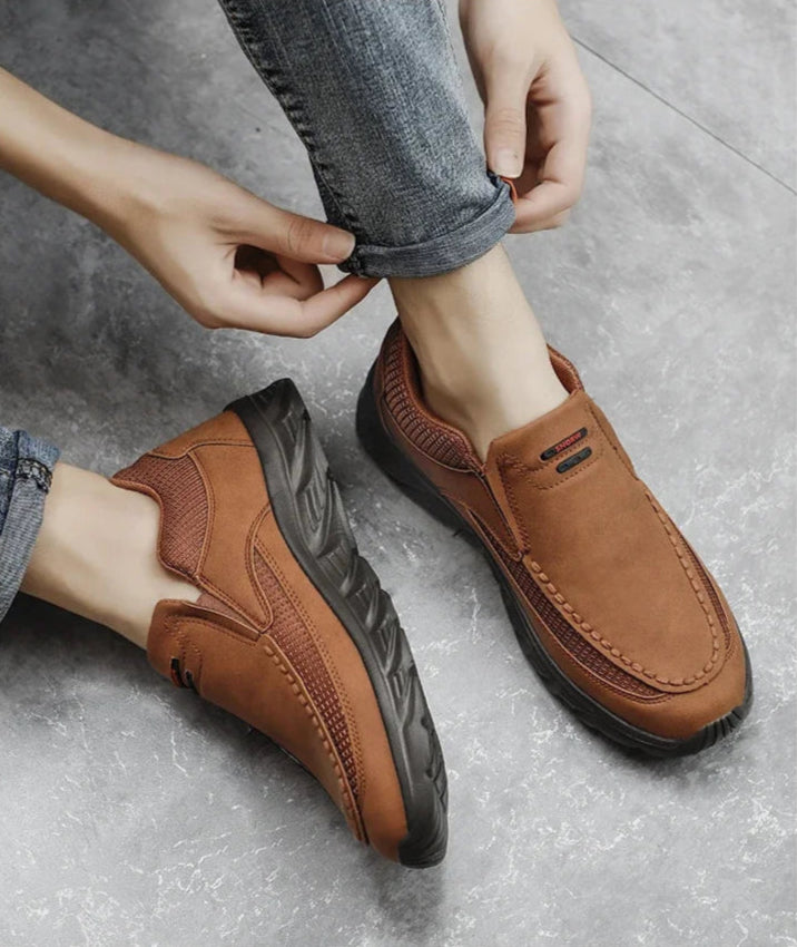Man adjusting jeans while wearing brown slip-on leather loafers