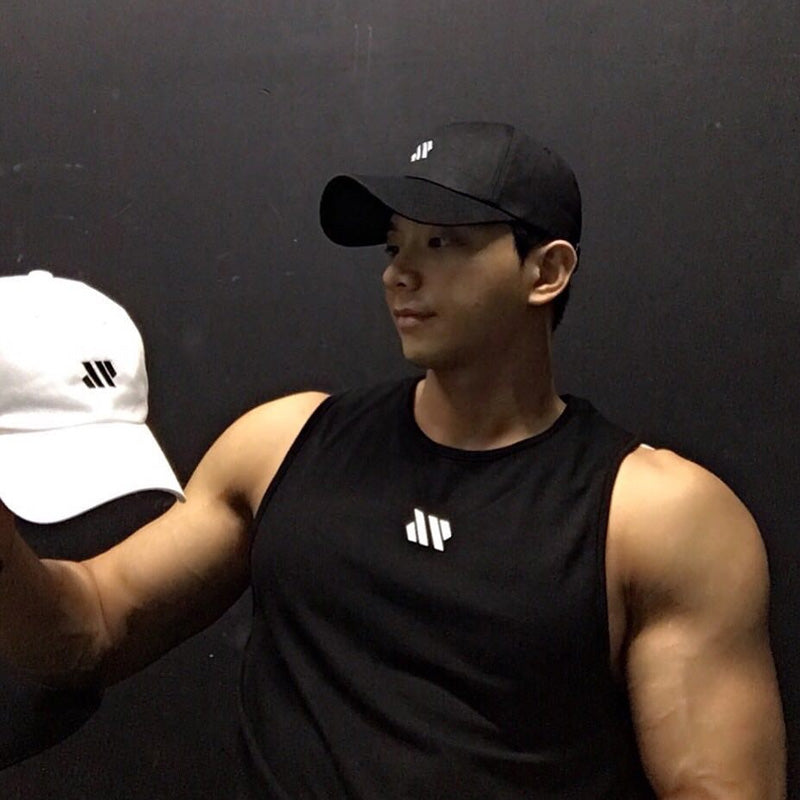 Man in black gym tank top and cap holding white cap with matching logo