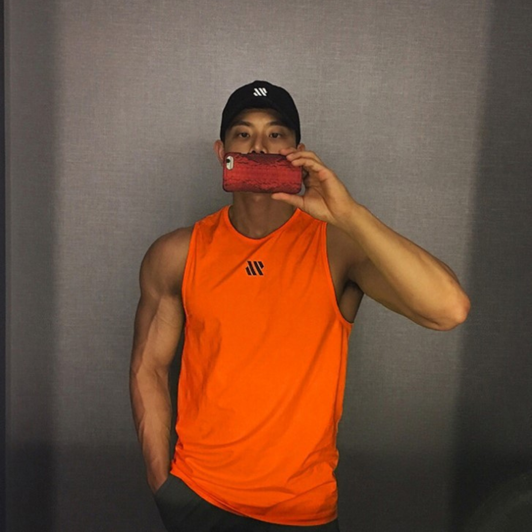 Man in orange quick-dry mesh tank top for workouts, athletic front pose in mirror