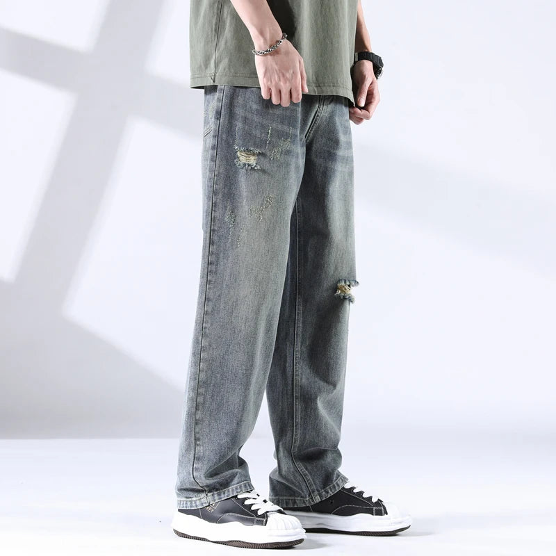 Men’s ripped stone-washed jeans in grey-blue tone, styled with casual tee and sneakers