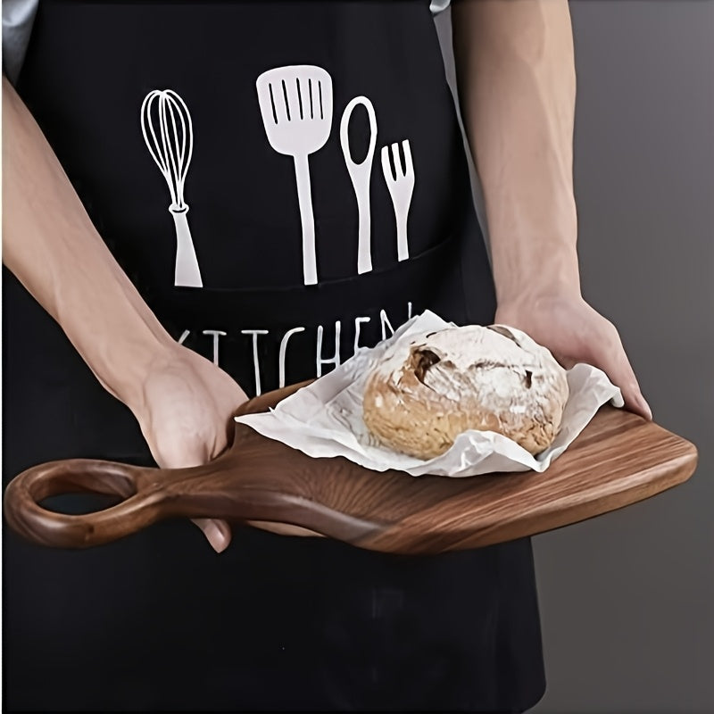 Person holding walnut cutting board with bread, wearing black kitchen apron