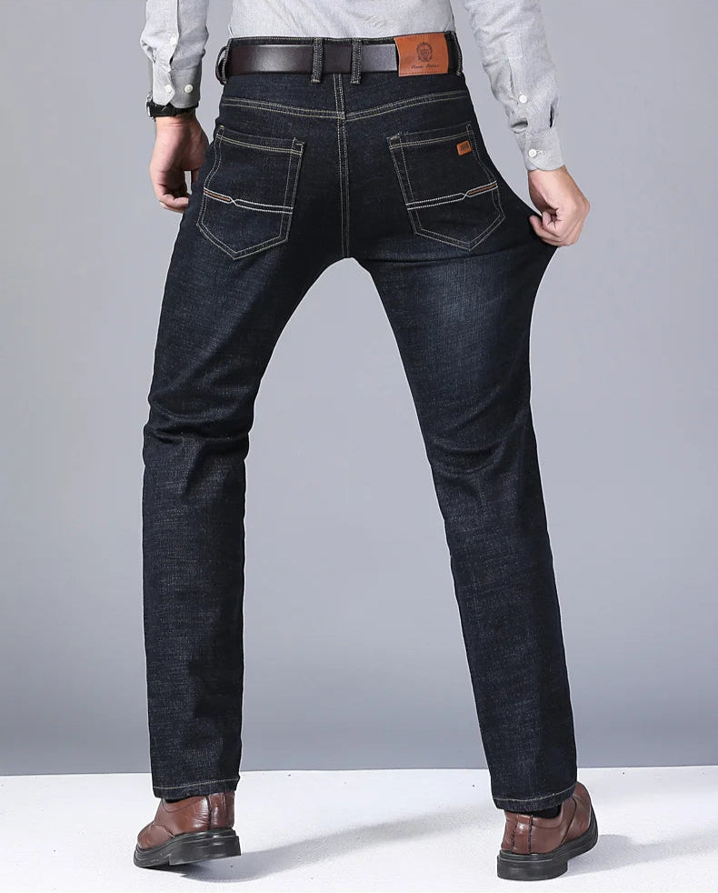 Rear view of model stretching black denim jeans to show fabric flexibility