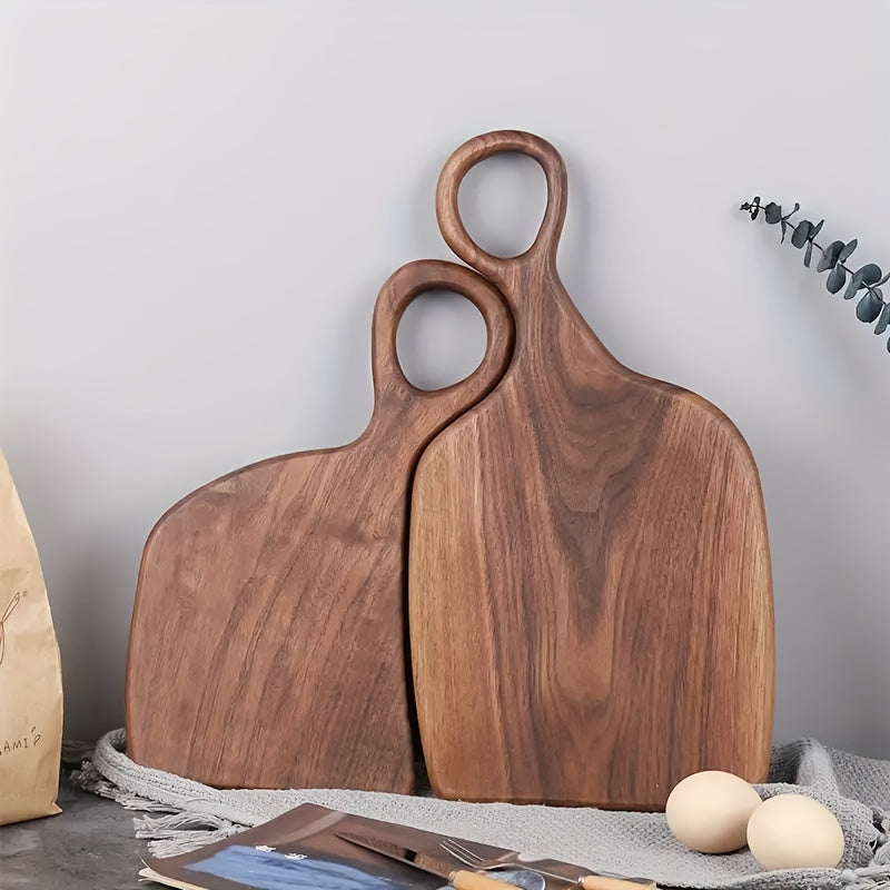 Set of two walnut cutting boards with loop handles standing upright on counter