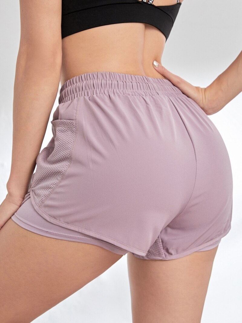 Side angle of pink dual-layer athletic shorts featuring deep mesh pocket and curved hem