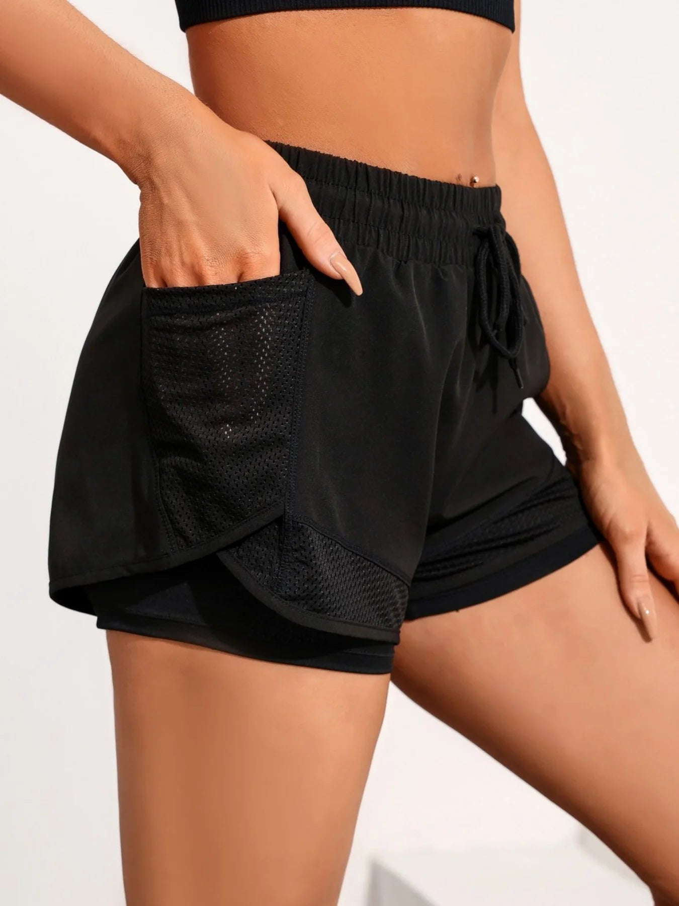 Side view of black workout shorts showing breathable mesh overlay
