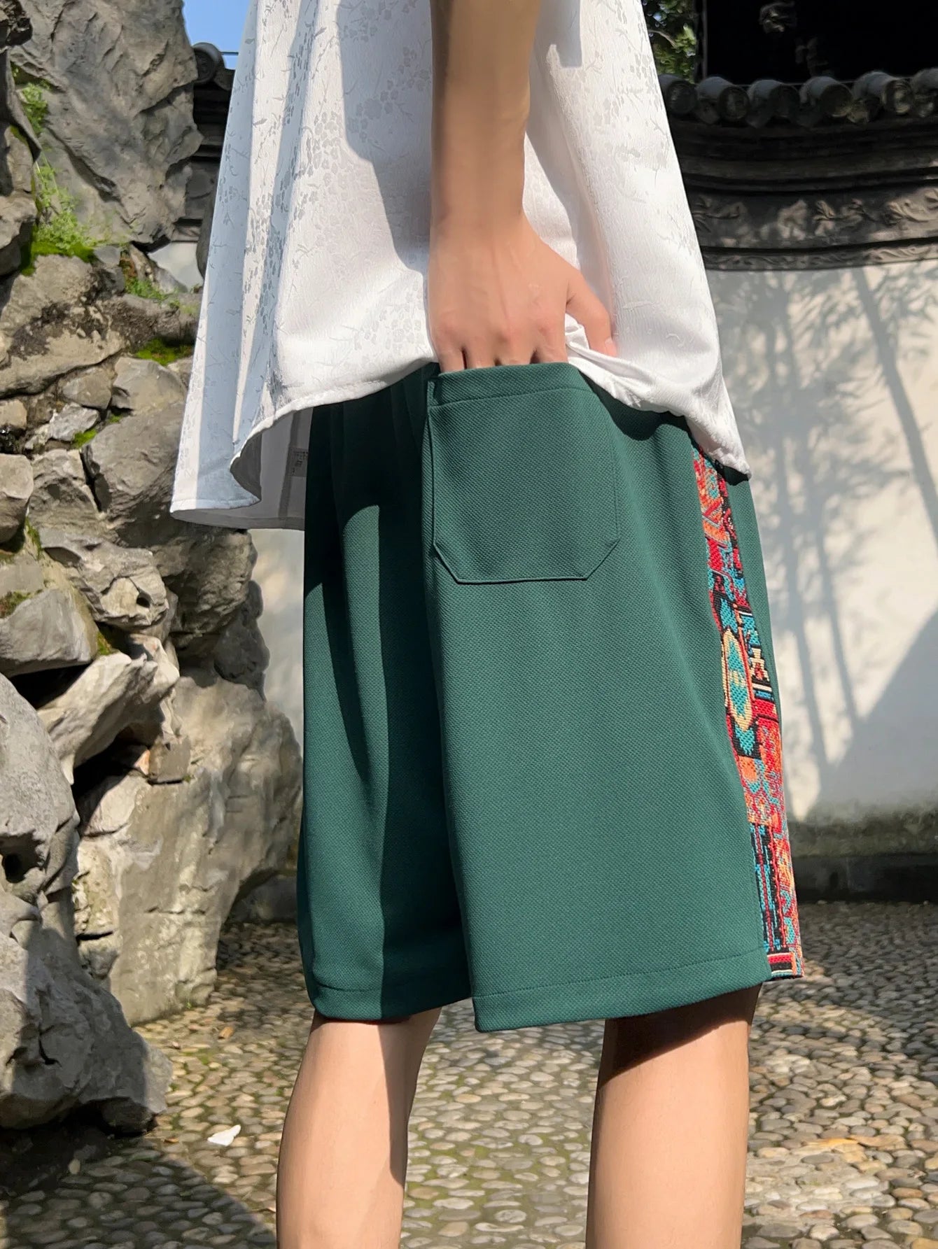 Side view of green ethnic patchwork shorts with back pocket and embroidered panel