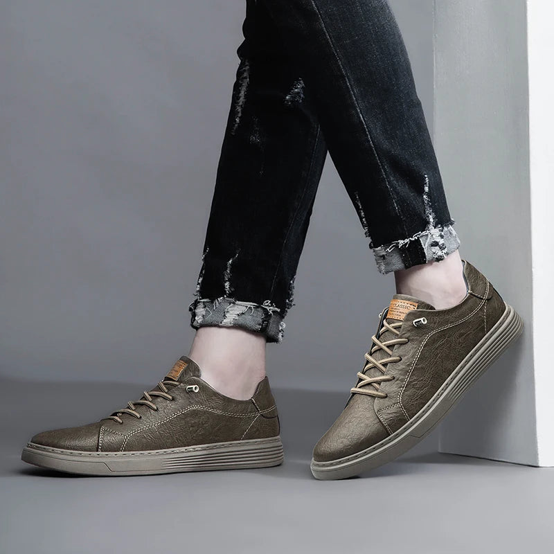 Side view of taupe leather sneakers in casual outfit, one foot on wall