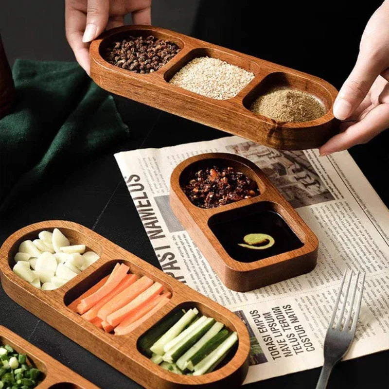 Solid wood condiment tray with three compartments holding ground spice, sesame, and peppercorns