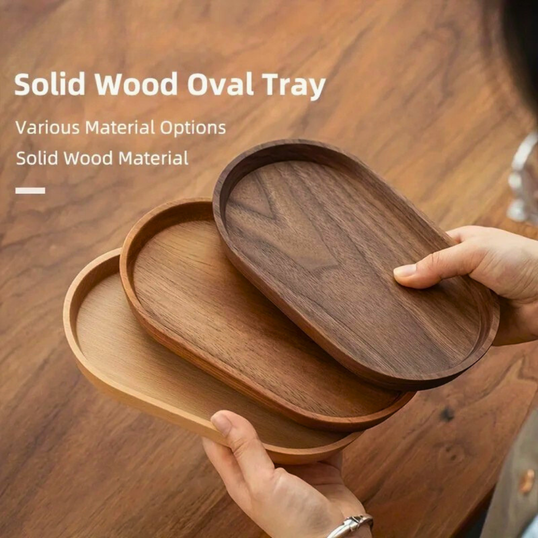 Three stacked Mokura oval trays in walnut, cherry, and beech finish on wooden surface