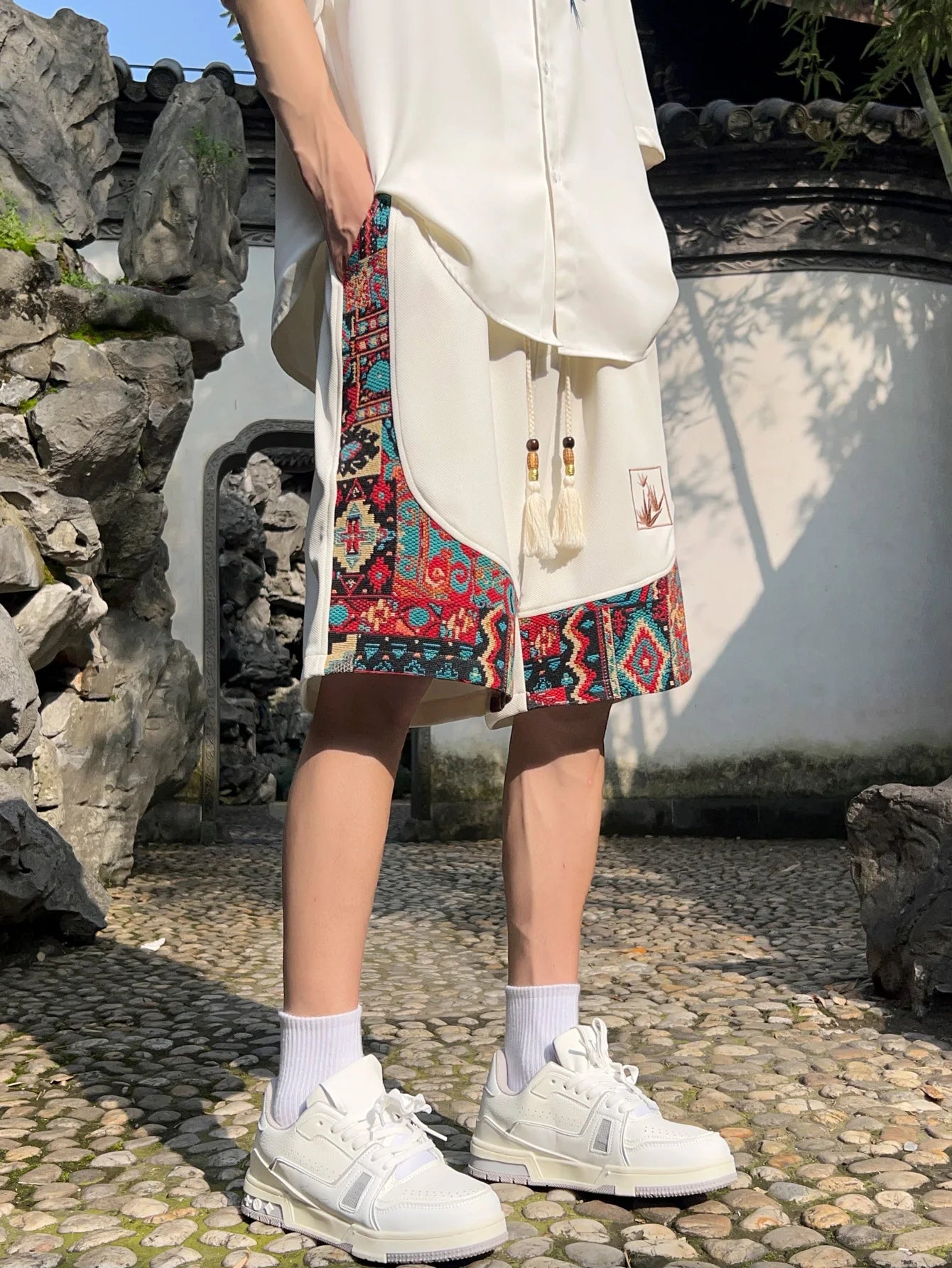 White ethnic shorts with bold woven panel trim and relaxed fit, front-side view