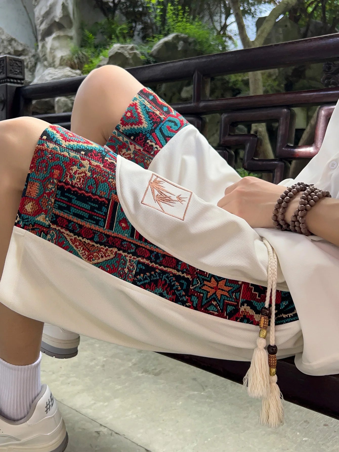 White ethnic shorts with colorful woven side panels, seated view