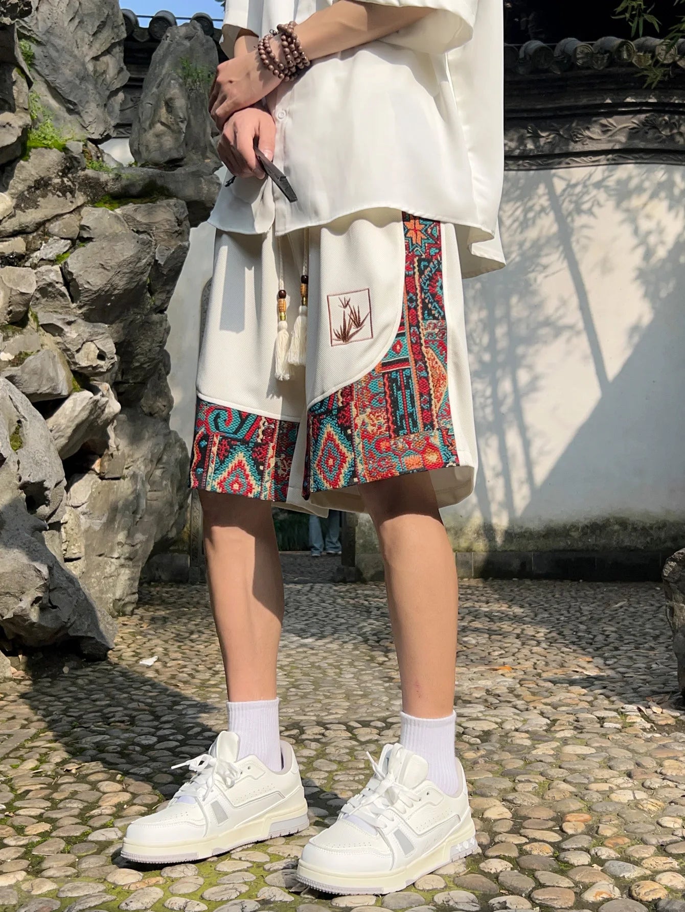 White shorts with front embroidered panel and tassel drawstring in outdoor setting